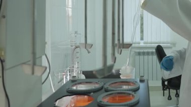 Koruyucu giysiler içindeki laboratuvar teknisyeni laboratuardaki otomatik karıştırıcıdan kimyasal örnekler alıyor. Kapat, Yavaş Hareket.