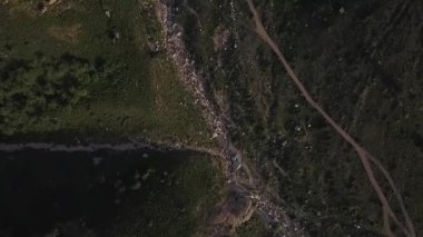 Güneşli bir bahar gününde yeşil örtülü bir dron dağların üzerinden uçar. Hava Görünümü.