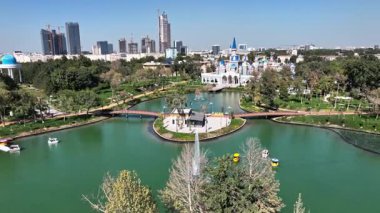 Şehir gölünün üzerinde, çeşmeleri ve sahilde bir şatosu olan bir dron. Güneşli bir yaz günü. Hava Görünümü, Yavaş Hareket