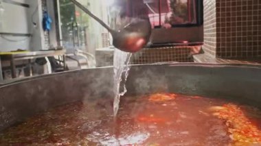 Şef, et çorbasını büyük bir kazanda sebzelerle karıştırıyor. Yavaş Hareket, Kapat.