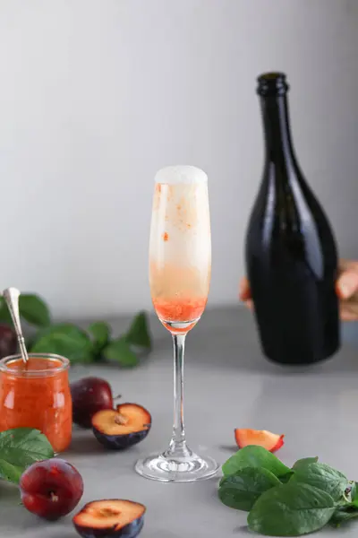 stock image Bellini plums champagne cocktail in crystal glass and fresh fruits on gray table. High quality photo