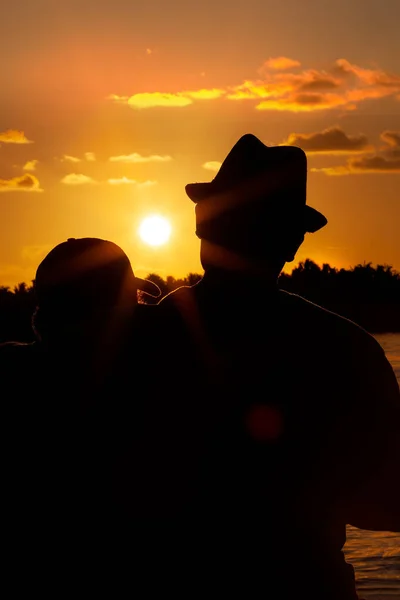 Silhouette of a man hugging his son watching the sunset at Key West, Florida, USA