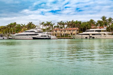 Miami, Florida, ABD - 09 Şubat 2024: Lüks yatlar Miami Milyarderler Sokağı 'nın rıhtımına yanaştı. Yatların arkasında çok sayıda malikane görülebiliyor ve kıyı şeridi palmiye ağaçları ile kaplı..