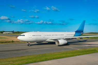 Punta Cana Havaalanı 'nda bir Airbus A330 kalkıyor. Uçak, mavi gökyüzü ve Dominik Cumhuriyeti 'nin tipik yeşil manzaraları arasında kalkışa hazırlanıyor..