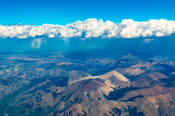 Arjantin Patagonya 'da, Bariloche ve Şili sınırı yakınlarındaki vadiler, tepeler ve dağların havadan görünüşü, uzak arkaplanda sağanak yağmur yağıyor..