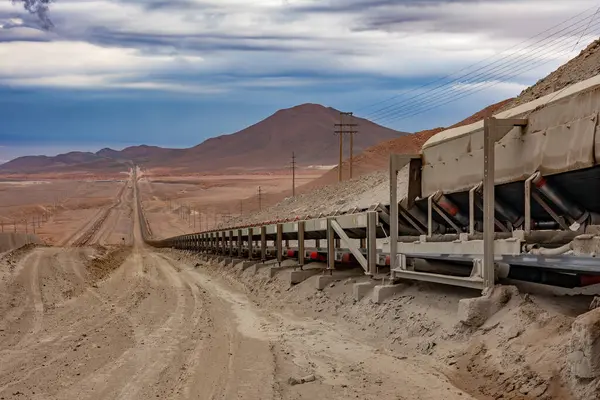 Mineraller, Şili 'de geniş bir bakır madeninde geniş bir taşıma bandı sistemi üzerinde taşınıyor. Madencilik sahasının engebeli arazisine yayılıyorlar..