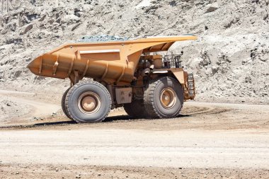 Şili 'deki büyük bir bakır madeninde büyük bir maden kamyonu nakliye malzemesi. Dağlık ve endüstriyel arka planda cüce gibi duruyor..