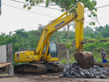 Malang, Indonesia -January 22, 2023 : Big yellow excavator digging construction site for building. the size of an excavator compared to a human