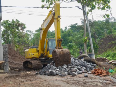 Malang, Indonesia -January 22, 2023 : Big yellow excavator digging construction site for building. the size of an excavator compared to a human