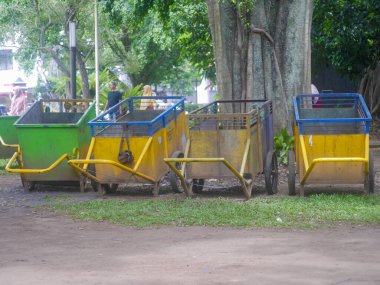 Garbage carts with different colors are parked in a row in the middle of the Malang town square