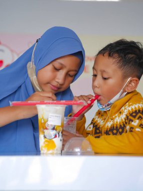 Malang, Indonesia -February 18, 2023 : two Indonesian children enjoying ice cream at shop originating from China which is currently viral and is being talked about by many people. selective focus