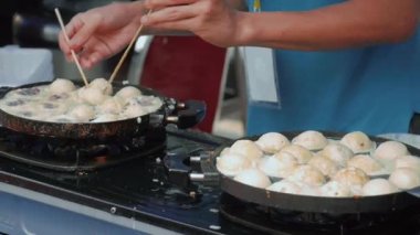 Festivaldeki sokak satıcıları kraker tavasında takoyaki veya takoyaki ızgarası pişiriyor.