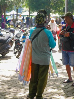 Malang, Endonezya -23 Şubat 2023: Yaşlı adam yol kenarında plastik oyuncaklar satıyor.