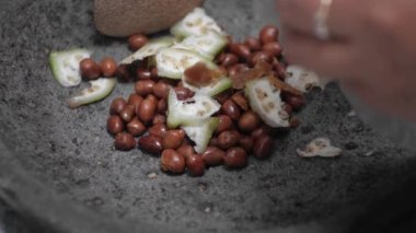 Fıstık, sakar muz ya da taş muz, esmer şeker ve petis, karides ezmesi ve kırmızı biber içeren bir havan topu kullanarak rujak baharatı elde etme süreci