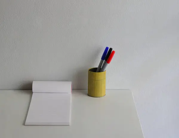 Beyaz ahşap masaya yerleştirilmiş renkli kalemleri ve not defteriyle yakın plan Çin tarzı kalem tutacağı.  