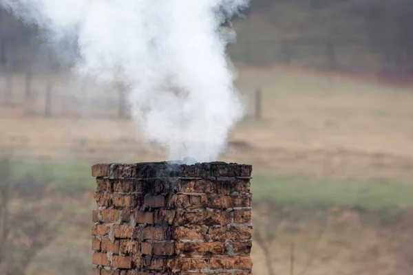 Old brick chimney and white smoke. House heating.