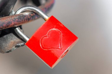 Köprüde kalp şeklinde kırmızı asma kilit. Aşkın soyut sembolü.