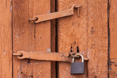 Eski ahşap bir kapıya asılmış bir asma kilit. Özel bölgeye geçiş yasaklanmıştır, yasaktır..