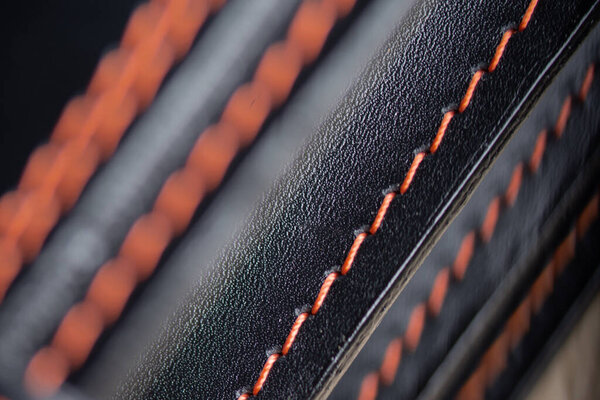 Черный кожаный фон. Текстура, искусственная кожа со стежком. Диагональный фрагмент швов на коже. Крупный план.