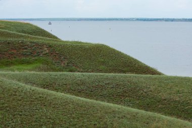 Tepeler deniz kenarında yeşil çimlerle kaplıydı. Baharda deniz manzarası.
