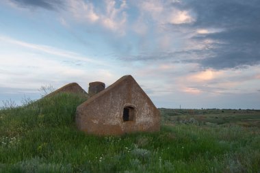Dışarıdaki eski taş bina. Çimlerle kaplı harabe bir çatı. Güzel bulutlu gökyüzü manzarası.