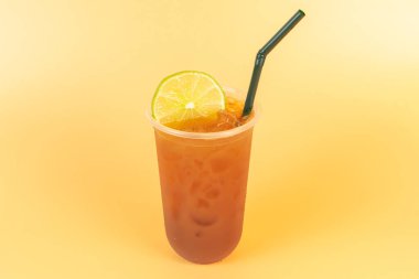 Cold brew tea or black tea with lemon in a plastic glasses on orange background.Refreshing drink to cool off in the summer. clipart