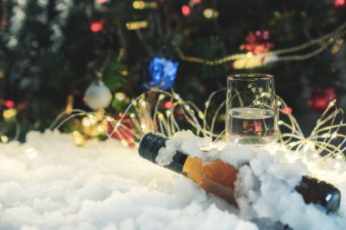Noel kutlaması şarabı ve bir bardak şarap karda ve Noel ağacı süslemesi arka planda bulanık noel arkaplan tasarımı, bokeh ışıklar