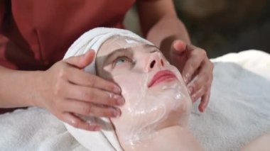 Beautiful young woman receiving face treatment and masks relaxing in spa salon, Close-up young women enjoying massage, Outdoor spa in gardens and natural light.