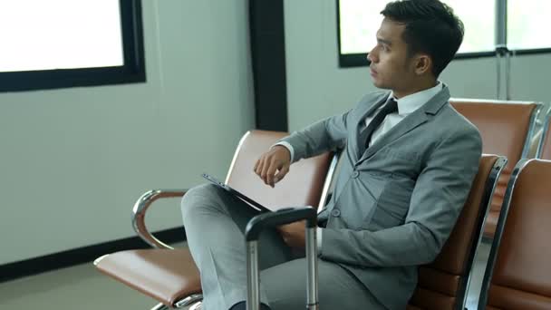 Молодий Бізнесмен Перевіряє Інформацію Планшеті Азійський Бізнесмен Сидить Стільці Аеропорту — стокове відео