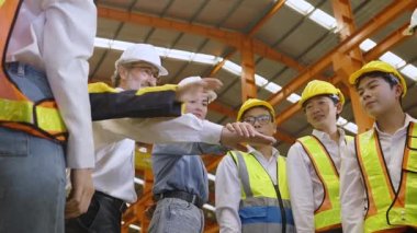 Yakın çekim ekibi, fabrikada güvenlik ekipmanı takan çok ırklı endüstriyel mühendisler büyük başarıyı el ele vererek kutluyorlar. Takım çalışması konsepti..