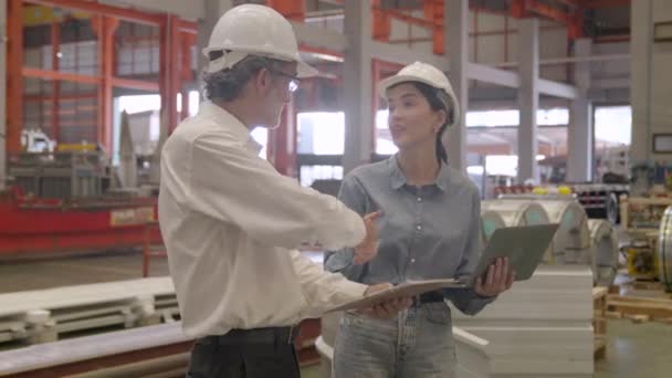 在一家宽敞的锌砖工厂里 一位男性工程师用他的笔记本电脑阐述了工作流程 而一位女性工程师则用心倾听并表达了她的同意 最终握手 — 图库视频影像