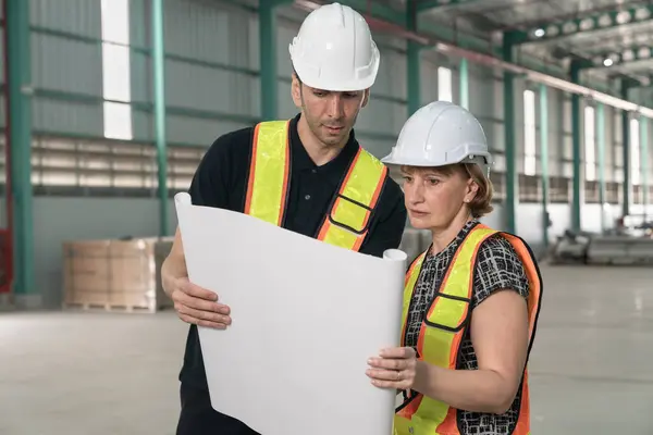 Engineer and female supervisor discussing a project plan at a construction site.
