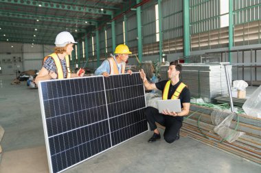Güvenlik donanımlı üç mühendis bir endüstriyel tesiste güneş paneli kurulumunu tartışıyor ve gözden geçiriyorlar..