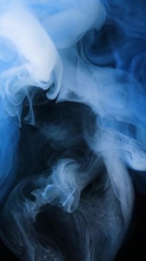 Suda dönen beyaz ve mavi mürekkebin soyut yakın çekimi.