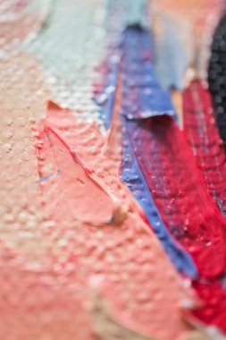 Bright hues of red, blue, and peach intertwine across the canvas, creating a dynamic visual texture. The thick application of paint showcases the artists expressive technique in layering. clipart