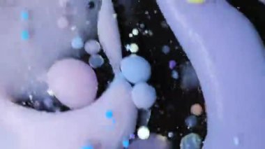 Renkli akrilik boya damlaları yağın içine bırakılır ve bu da dönen desenlerin ve dokuların dinamik bir görüntüsünü oluşturur..