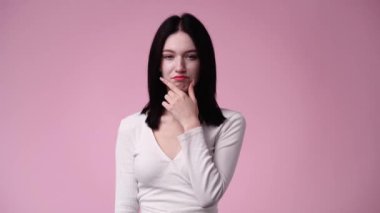 Pembe arka plan üzerinde düşünen genç bir kadının 4K videosu..