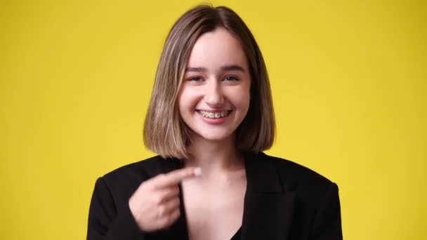 黄色の背景の上に何かを提示若い女性の4Kビデオ 発表の概念 — ストック動画