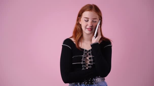 ピンクを背景に孤立した電話で話す可愛い女の4K動画 技術の概念 — ストック動画