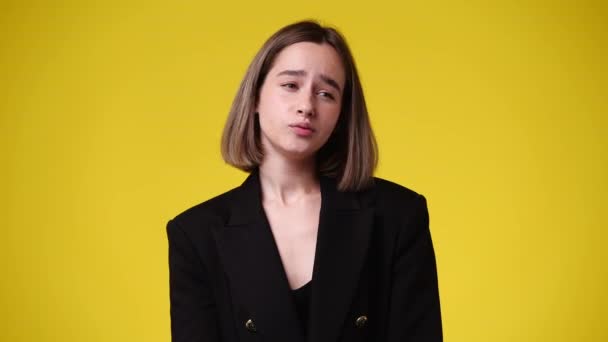 黄色の背景の上に考え 下を向いている若い女性の4K動画 思考の概念 — ストック動画