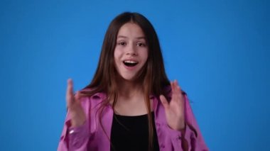 Heyecanlı kızın mavi arka planda el çırpışının 4K videosu. El çırpma kavramı.