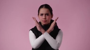 Pembe arka planda çapraz elleri olan bir kızın 4K videosu. Olumsuz duygu kavramı.