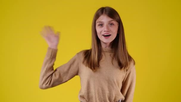 黄色の背景にこんにちはを振っている1人の女の子の4Kビデオ 感情の概念 — ストック動画