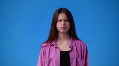 Mavi arka planda çapraz elleri olan bir kızın 4K videosu. Olumsuz duygu kavramı.