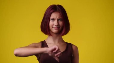 Pembe arka planda parmağını gösteren bir kızın 4K videosu. Olumsuz duygu kavramı.