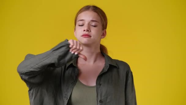 一个女孩在黄色背景下显示大拇指的4K视频 负面情绪的概念 — 图库视频影像