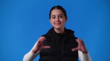 Kızın elleri mavi arka planda kalp şeklini aldığı 4k 'lık video. Aşk duygusu kavramı.