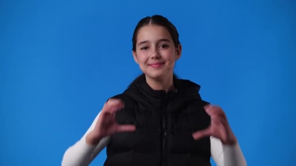 4K视频中的女孩用双手在蓝色的背道上做心形 爱情的概念 — 图库视频影像