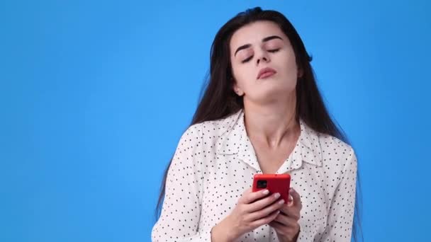 4K段女性在蓝色背景下使用手机的视频 感情的概念 — 图库视频影像