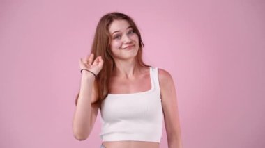 Pembe arka planda iyi işareti olan bir kızın 4K videosu. Duyguların kavramı.